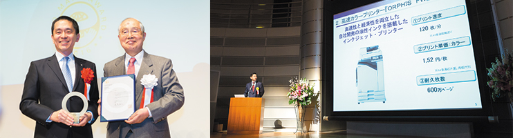 公益財団法人日本環境協会の森嶌昭夫代表理事と羽山明社長。開発担当者によるプレゼンテーションの様子。